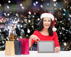 Image showing smiling woman in santa hat with bags and tablet pc