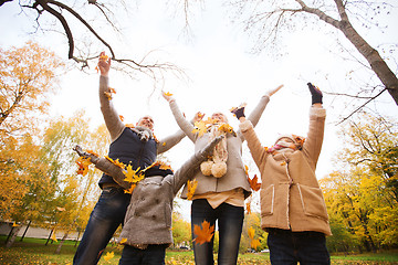 Image showing happy family playing with autumn leaves in park