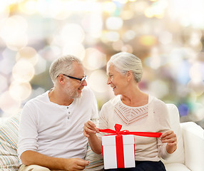 Image showing happy senior couple with gift box at home