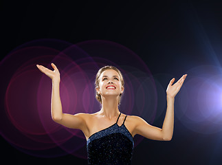 Image showing smiling woman raising hands and looking up