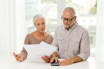 Image showing senior couple with papers and calculator at home