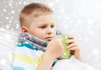 Image showing ill boy with flu in bed drinking from cup at home