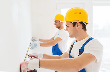 Image showing smiling builders with measuring tape indoors