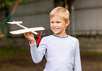 Image showing smiling little boy holding a wooden airplane model