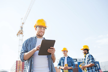 Image showing smiling builders in hardhats with tablet pc