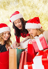 Image showing smiling young women in santa hats with gifts