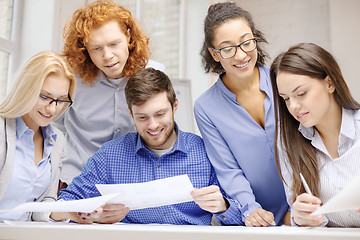 Image showing smiling team with paper at office