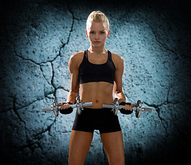 Image showing young sporty woman with dumbbells flexing biceps