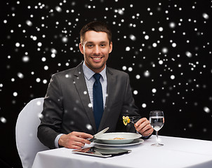 Image showing smiling man with tablet pc eating main course