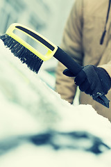 Image showing man cleaning snow from car windshield with brush