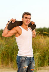 Image showing smiling teenage boy with skateboard outdoors