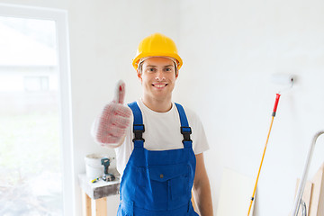 Image showing smiling young builder in hardhat showing thumbs up