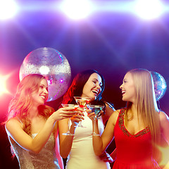 Image showing three smiling women with cocktails and disco ball