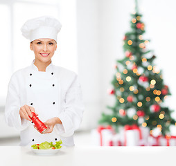 Image showing smiling female chef spicing vegetable salad