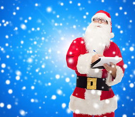 Image showing man in costume of santa claus with notepad