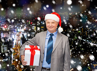 Image showing smiling man in suit and santa helper hat with gift