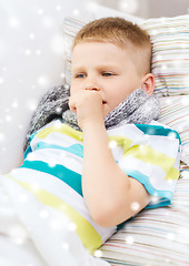 Image showing ill boy with scarf lying in bed and coughing