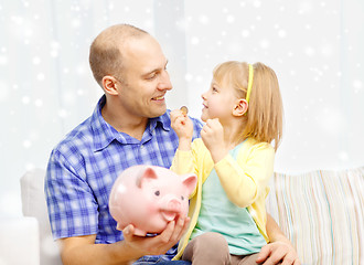 Image showing happy father and daughter with big piggy bank