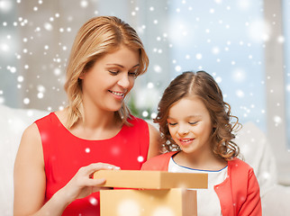 Image showing smiling mother and daughter with gift box at home