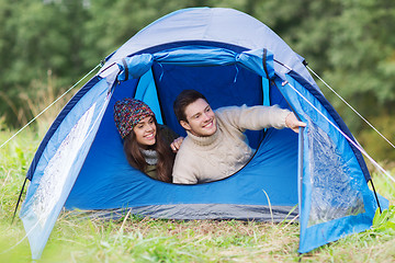 Image showing smiling couple of tourists looking out from tent