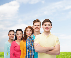 Image showing group of smiling teenagers over blue sky and grass