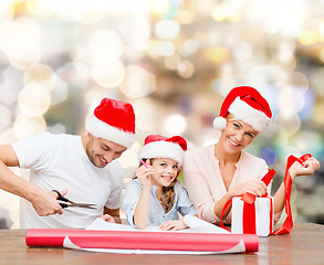 Image showing happy family in santa helper hats packing gift