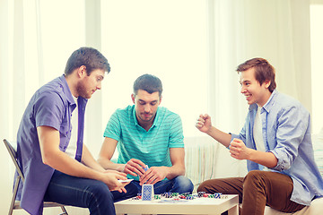 Image showing happy three male friends playing poker at home