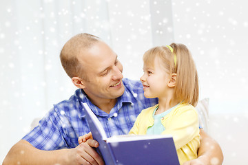 Image showing smiling father and daughter with book at home