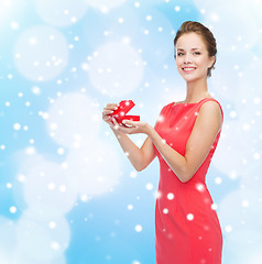 Image showing smiling young woman in red dress with gift box