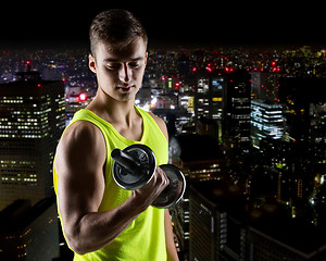 Image showing young man with dumbbell flexing biceps