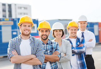 Image showing group of smiling builders in hardhats outdoors