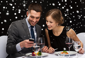 Image showing smiling couple with smartphone at restaurant