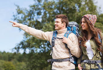 Image showing smiling hikers with backpacks pointing finger