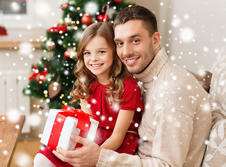 Image showing smiling father and daughter with gift box at home