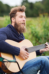 Image showing smiling man playing guitar in camping