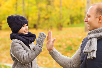 Image showing happy father and son making high five in park