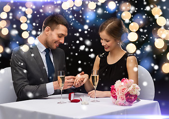 Image showing smiling couple with red gift box at restaurant