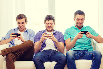 Image showing smiling friends with smartphones at home