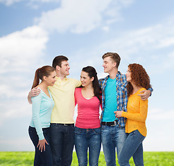 Image showing group of smiling teenagers over blue sky and grass