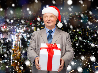 Image showing smiling man in suit and santa helper hat with gift