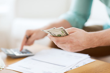 Image showing close up of man counting money and making notes