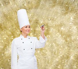 Image showing smiling female chef writing something on air