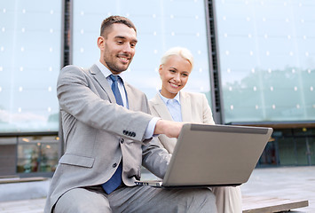 Image showing smiling businesspeople with laptop outdoors