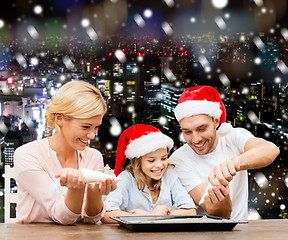 Image showing happy family in santa helper hats cooking