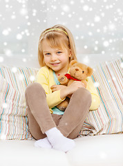 Image showing smiling girl with teddy bear sitting on sofa