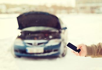 Image showing closeup of man with broken car and smartphone