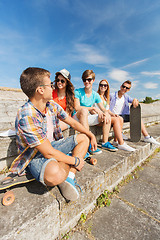 Image showing group of smiling friends sitting on city street