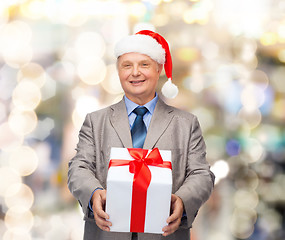 Image showing smiling man in suit and santa helper hat with gift