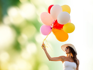 Image showing smiling young woman in sunglasses with balloons