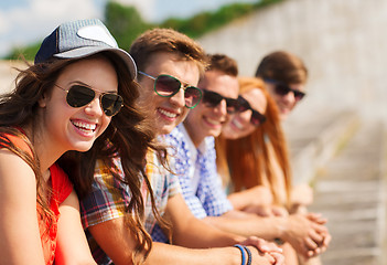 Image showing close up of smiling friends sitting on city street